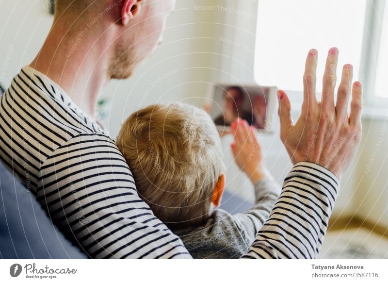 Father and son having video call to mother family internet technology modern people home chat computer communication woman young happy online wireless