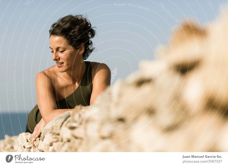 A selective focus shot of a beautiful female Latina lying on a rocks woman girl pretty beauty young white black adult portrait attractive people caucasian