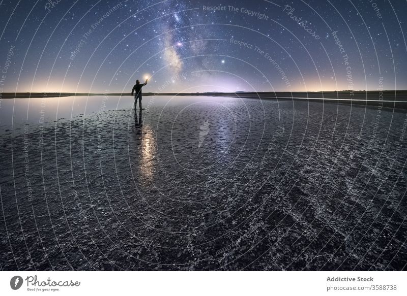 Silhouette of man on lonely shore in starry night nature silhouette reach out sky milky way stand wish catch shooting star coast torch water sea ocean calm