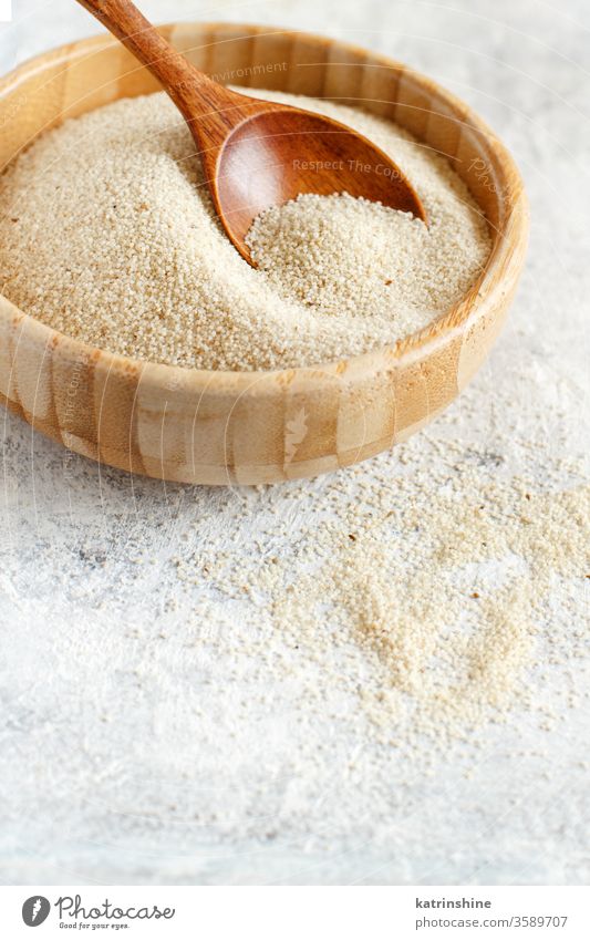 A bowl of raw fonio seeds with a spoon dry Raw uncooked wooden copy space white background close up african cereal food nutriment organic vegan vegetarian