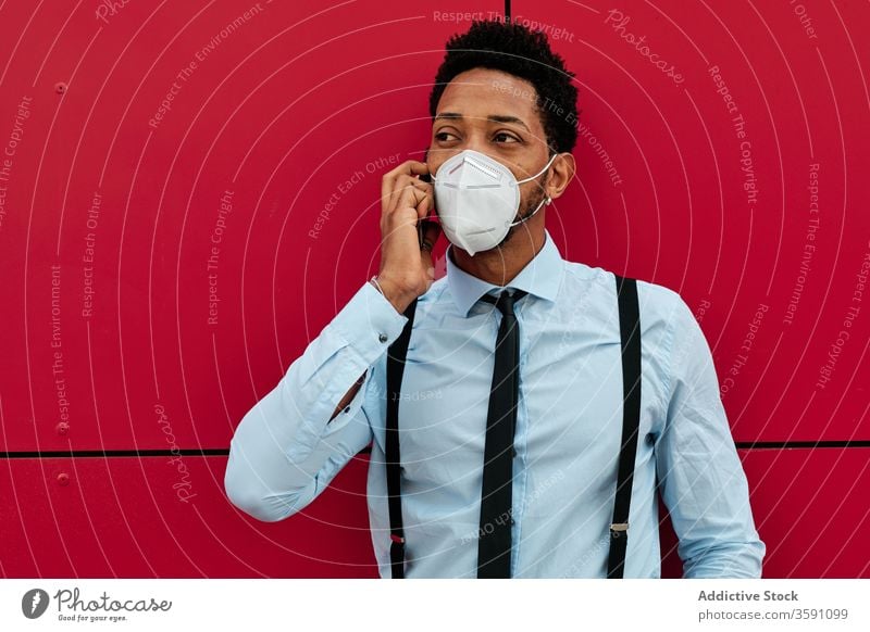 Serious ethnic businessman in respirator talking on smartphone on street phone call mask protect city pandemic infection virus entrepreneur coronavirus epidemic