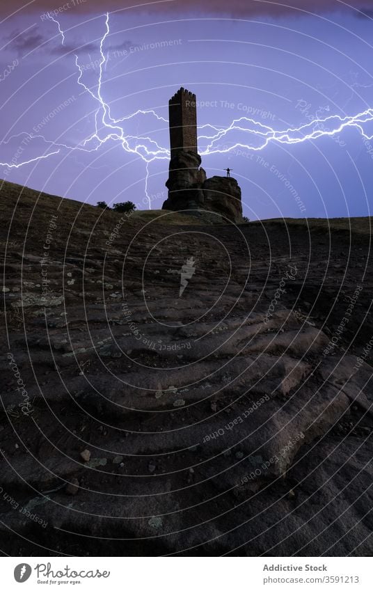 Stormy sky with lightning over stone tower storm rough dramatic dark rock person weather construction building formation twilight power gloomy atmosphere energy