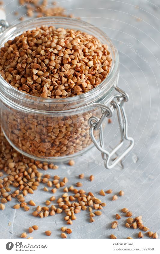 Raw dry buckwheat grain  in a jar Buckwheat food ingredient gluten free close up copy space negative space grey neutral brown rustic cuisine healthy heap pile