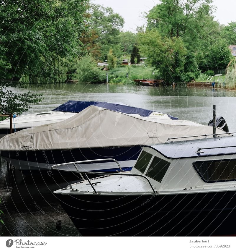 Small motorboats are moored on the banks of the river Havel near Oranienburg, bushes and trees in the background Motorboat tarpaulin Water River green Nature