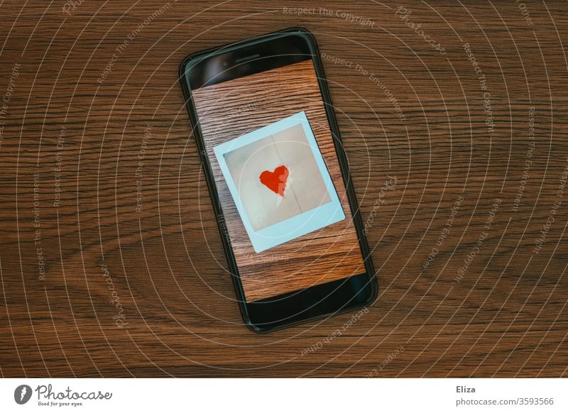 A photo with a heart on the screen of a smartphone. Online dating. Tinder. Communication. Heart Love Screen display Polaroid symbol communication Emotions Chat