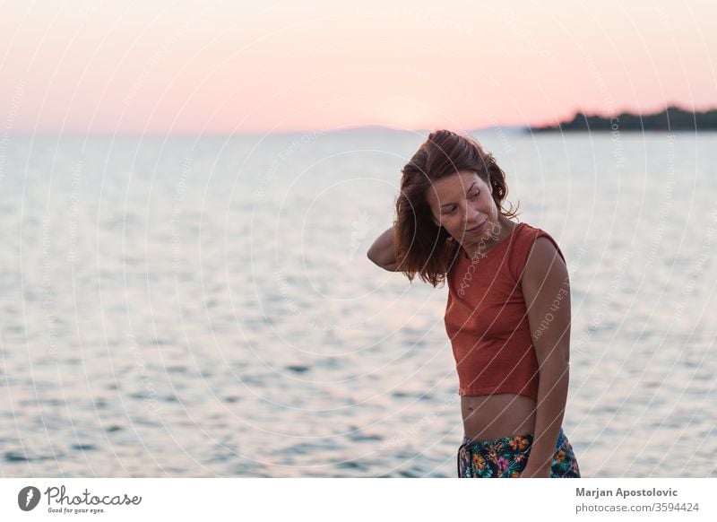 Young woman enjoying sunset by the beach female casual happy lifestyle sunrise sea ocean water travel vacation holiday summer freedom outdoors tourism seaside