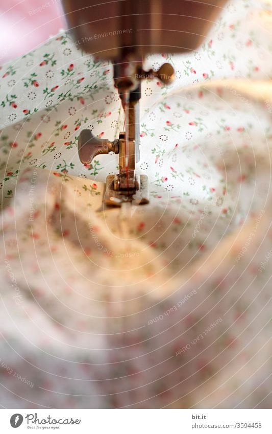 Detailed view of sewing machine foot, quilting foot sewing, quilting the floral fabric. Bright, white sewing work with cotton fabric in the light of the sewing machine. Work, gainful employment in the tailor craft in tailoring, workshop, sewing room, studio, sewing shop, factory.