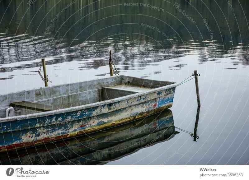 Tied up empty old boat leash nostalgically Lake River bank Water Exterior shot Calm Empty melancholy Old bluish reflection Reflection Weathered tranquillity