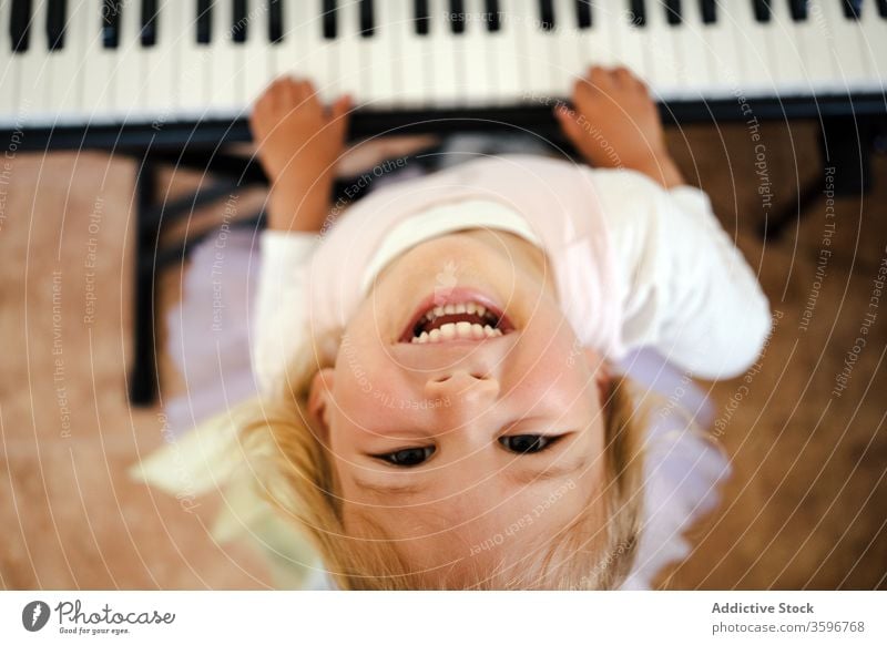 Laughing girl playing piano looking up at camera home synthesizer fun laugh happy study smile childhood toddler cute music class skirt schoolgirl education