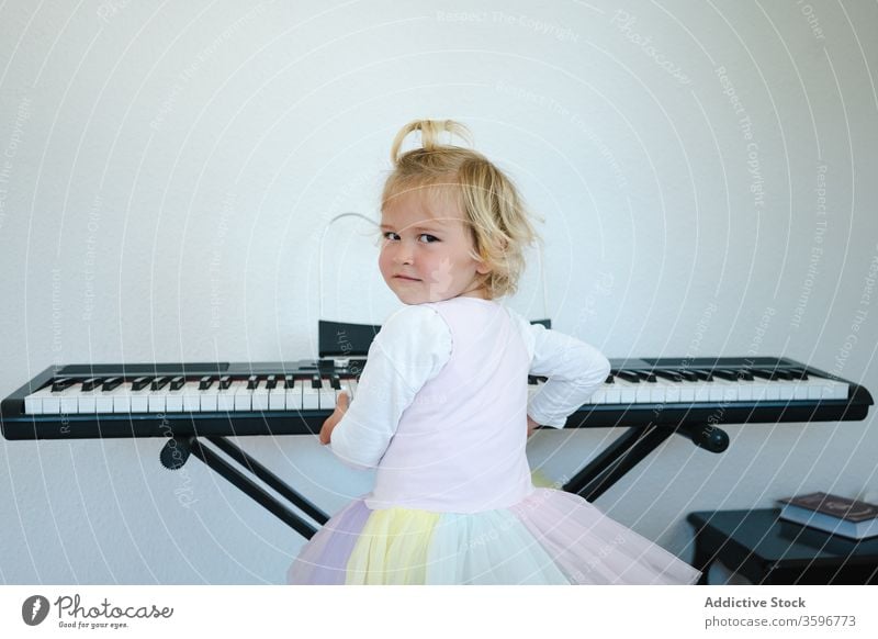 Cute girl learning to play modern piano home synthesizer study childhood cute music class skirt schoolgirl education practice prepare little adorable activity