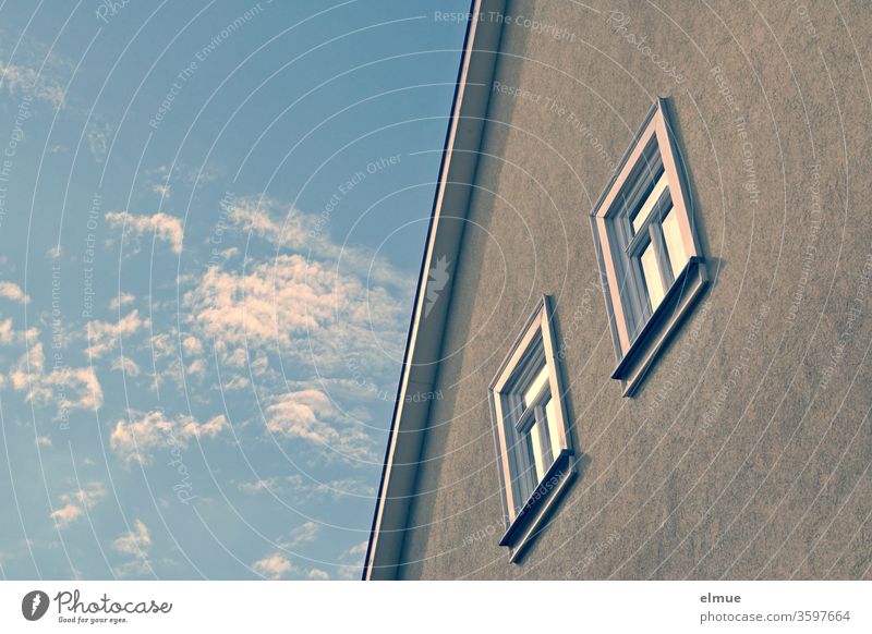 Partial view of a house facade with roof edge and two windows as well as fair weather clouds in the sky Window Clouds in the sky reflection Wooden window