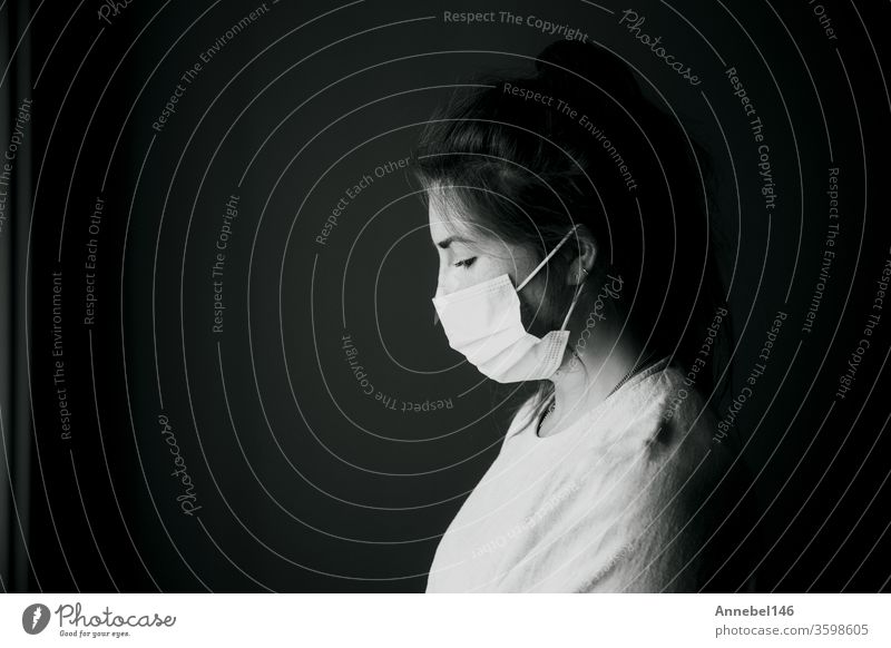 Young woman wearing protection mask against Covid-19, Coronavirus looking depressed and isolated, black and white portrait virus concept background medical