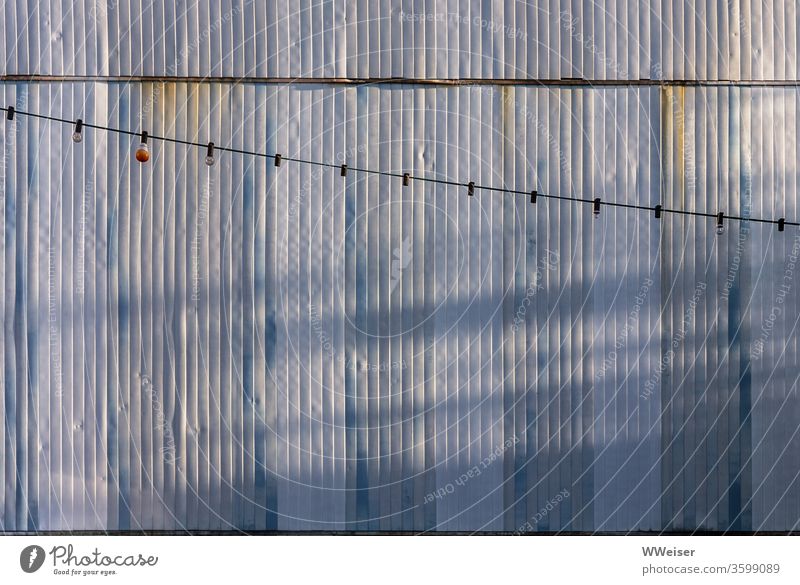 Light chain in front of the corrugated iron wall of a container, evening light Fairy lights Light bulbs lamps Lighting String decoration Garden festival