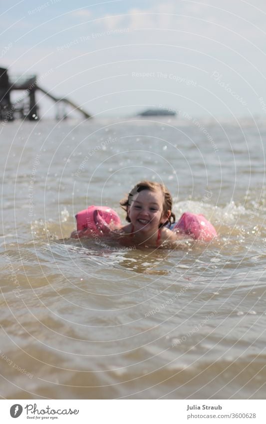 Infant with a waterwing bathing in the North Sea bathe chill Fresh Swimming & Bathing Drop Drops of water Water Ocean Footbridge girl Comical muck about Waves