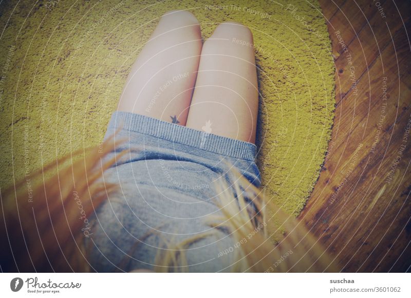 sitting on the floor looking at your own legs | symmetry Woman feminine Legs Feminine Carpet sedentary hair wooden floor Tattoo Stars Symmetry Interior shot