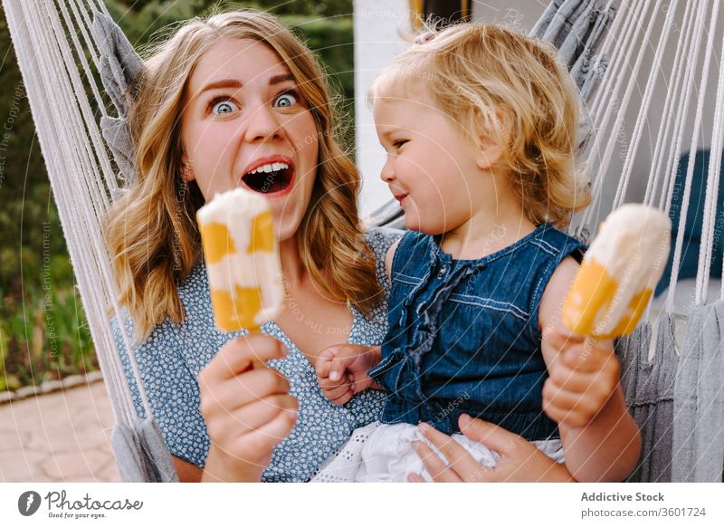 Happy little girl and woman with homemade popsicles mother daughter hug lolly ice enjoy cheerful summer terrace smile ice cream toddler female together