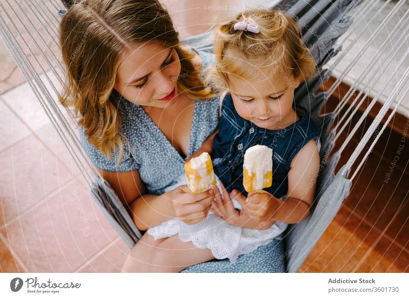 Happy little girl and woman with homemade popsicles mother daughter hug lolly ice enjoy cheerful summer terrace smile ice cream toddler female together