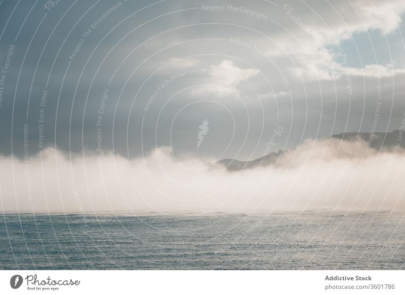 Calm sea near hill under cloudy sky in foggy weather seascape mist breathtaking picturesque nature spectacular spain mountain peace mundaka idyllic biscay