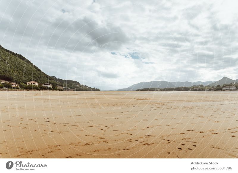 Sandy seashore near hill with houses under cloudy sky sand forest nature harmony picturesque idyllic hillside reserve beach serene horizon peace peaceful