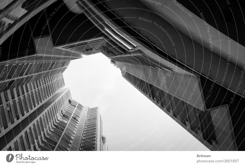 Bottom view of skyscraper building against gray sky and clouds. Looking up view in apartment building in the city. Real estate and corporate construction. Multi-storey residential building. Condo.