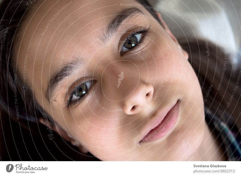 Portrait of a beautiful young caucasian tanned girl on a white background closeup. Long eyelash and natural brown eyebrows, green eye, beauty concept