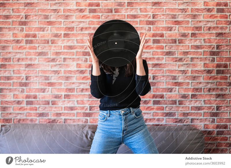 Anonymous young woman holding a black vinyl with her hands beautiful girl music disco female fashion sound background portrait person audio people entertainment