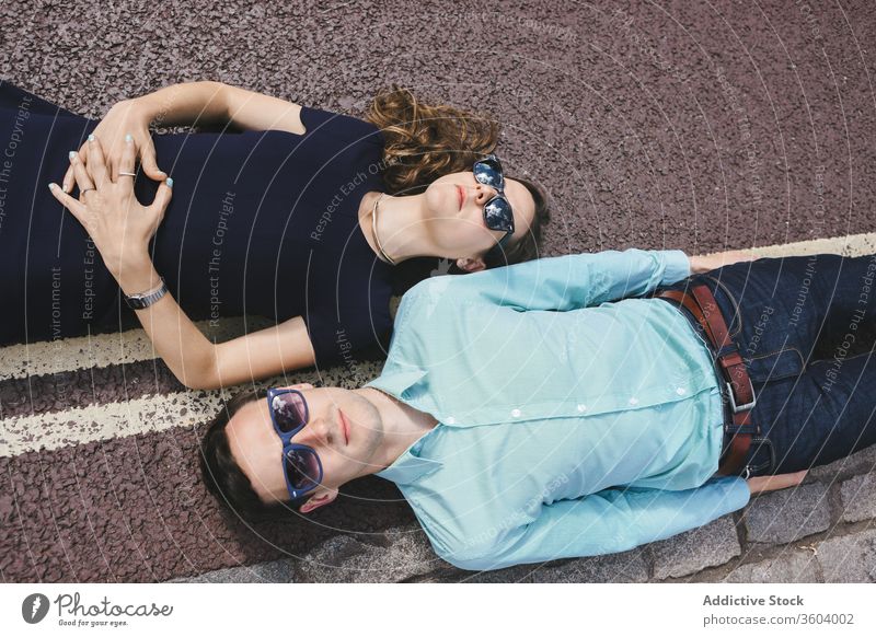 Unemotional couple lying on asphalt road in city eccentric style unemotional chill ridiculous roadway london england united kingdom relax relationship weekend