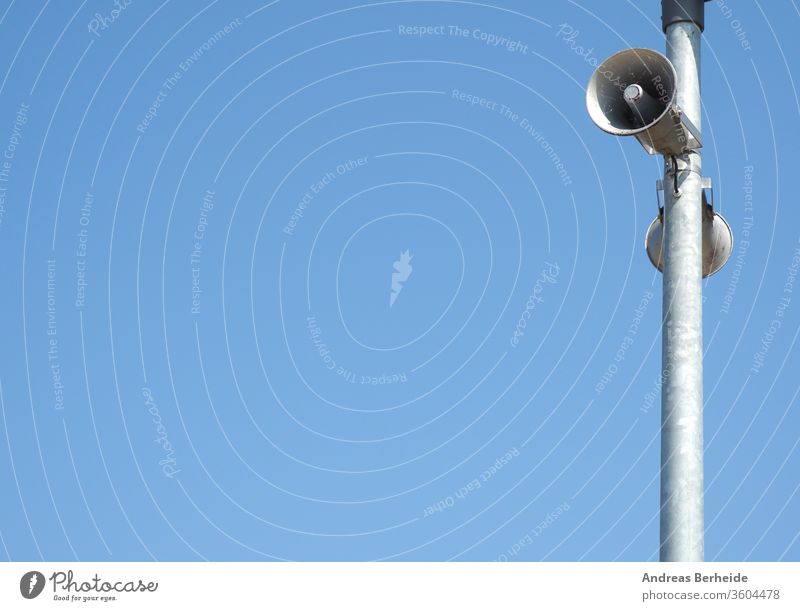 Loudspeakers on a lamppost against a blue summer sky loudspeaker broadcast steel communication urban siren streetlight streetlamp security warning sound space