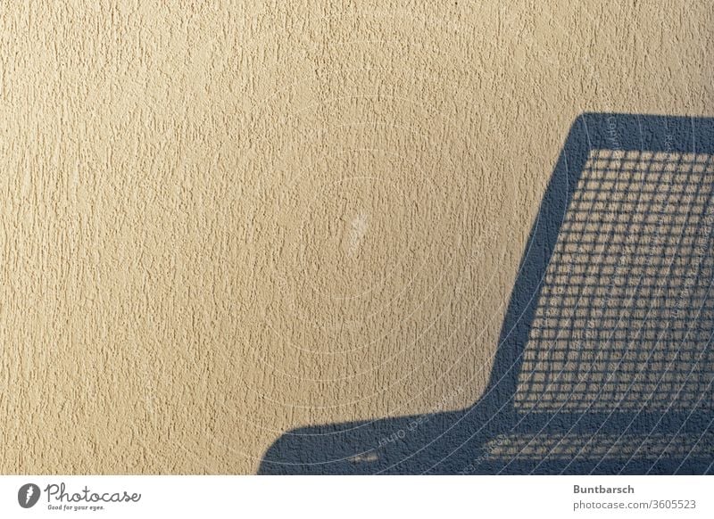 Shadow of a metal bench on a rough plaster wall Bench Roughcast wall roughcast Wall (building) Deserted bailer Wall (barrier) Colour photo Copy Space bottom