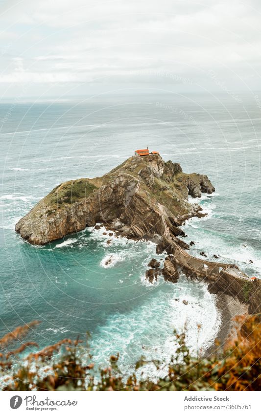 Rocky hillside near ocean under cloudy sky sea rock house wave picturesque seascape breathtaking nature idyllic harmony paradise skyline peaceful marine