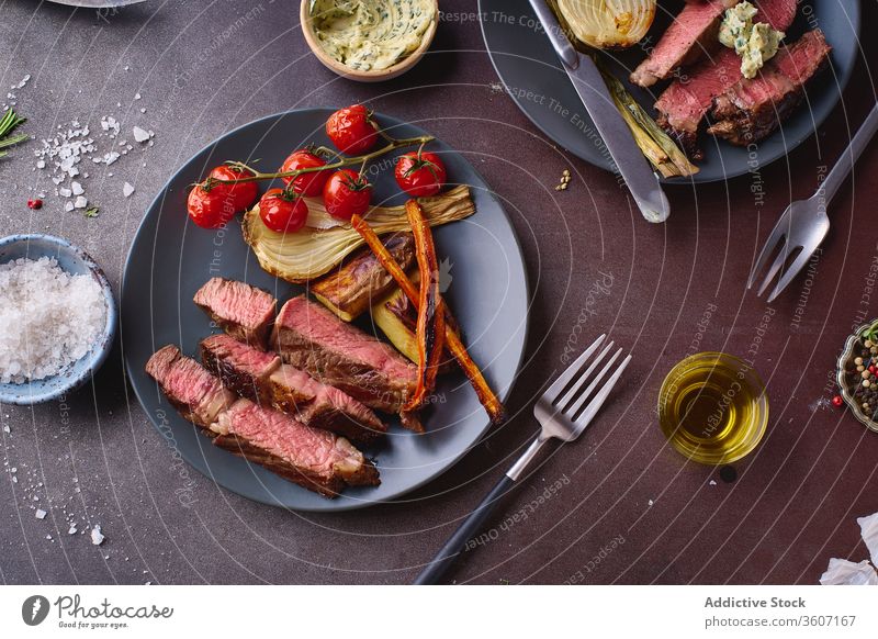 Dish of cooked beef meat on table ribeye steak grilled black angus food cuisine spice beefsteak roasted tasty sliced closeup salt cooking filet protein fresh