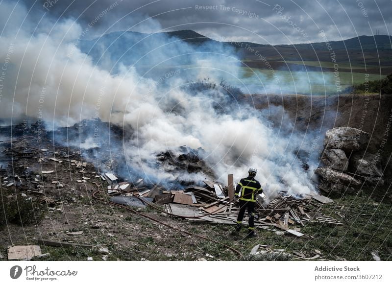 Firefighter putting out fire with water firefighter fireman brave hose extinguish smoke put out uniform male protect work equipment job stand occupation helmet