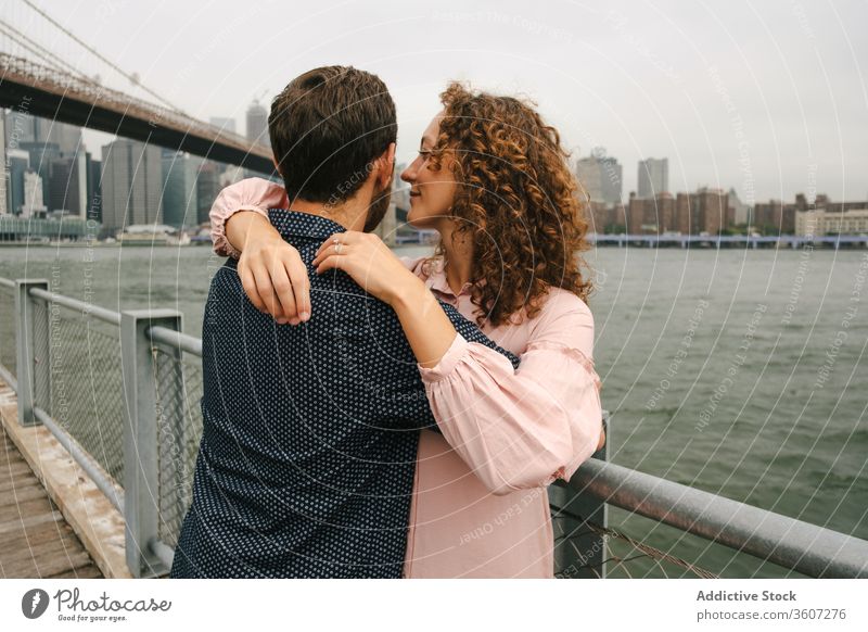 Happy couple embracing on embankment embrace promenade stroll city relationship river hug brooklyn bridge new york america united states usa wooden smile