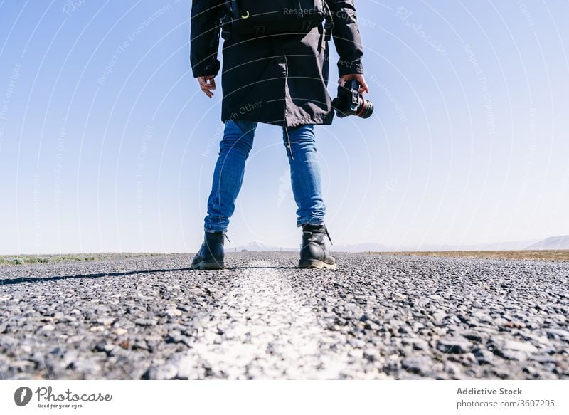 Crop male photographer on road man professional traveler landscape picturesque asphalt photo camera cold iceland photography roadway adventure outerwear season