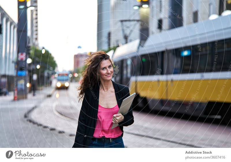 Businesswoman with laptop on city street entrepreneur businesswoman confident cityscape formal well dressed professional female cheerful content smile determine