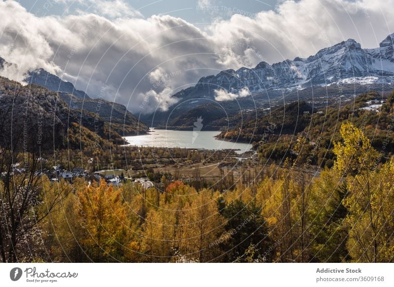 Lake near snowy mountains in autumn lake ridge water sky cloudy root tree old calm coast village range weather countryside nature tranquil landscape serene