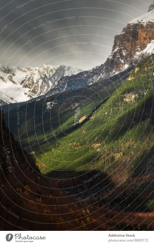 Valley and snowy mountains against overcast sky valley ridge storm weather gray green nature range landscape cold rock scenic season terrain cool environment