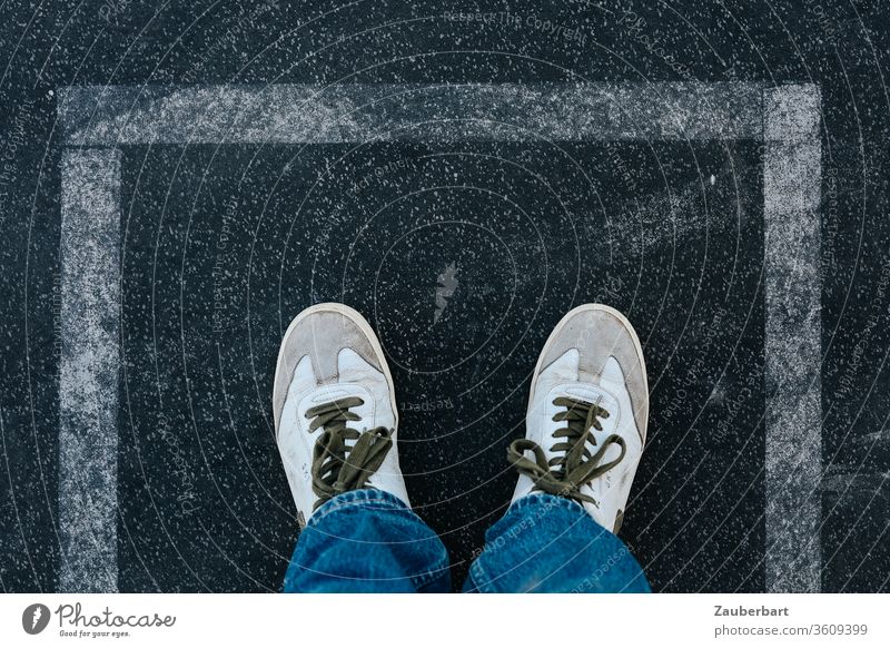 White sneakers on asphalt in rectangular boundary of white lines Line Rectangle Asphalt Border Boundary stop holds shoelaces jeans Exit route mark