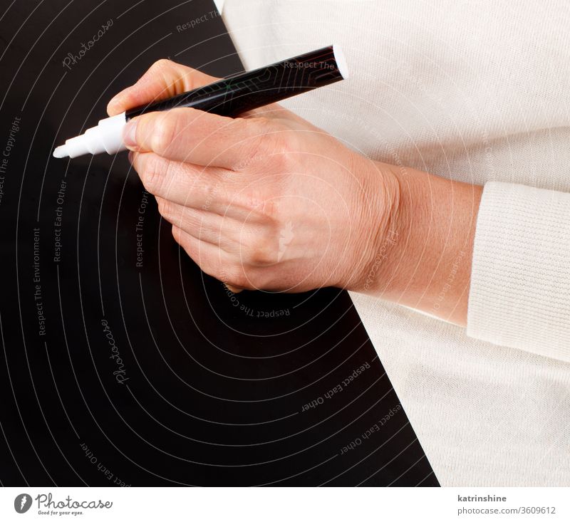 Woman writing on a black chalkboard keeping small close up hands body blackboard school educational faceless trendy