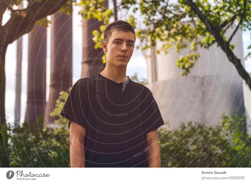 portrait of a serious young man in front of an industrial plant adolescent beautiful boy building casual caucasian chimney confident culture facility future