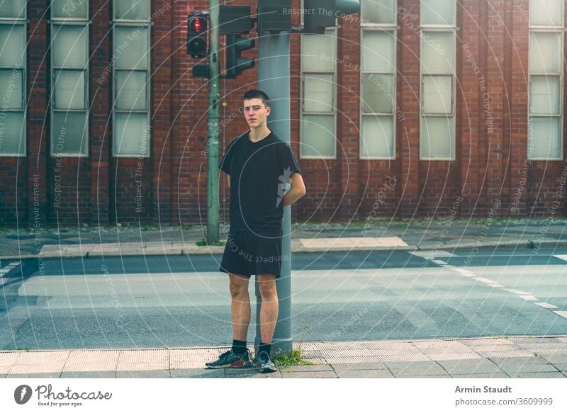 portrait of a lonely young man standing at a red traffic light street adolescent beautiful boy building casual caucasian confident culture future issues