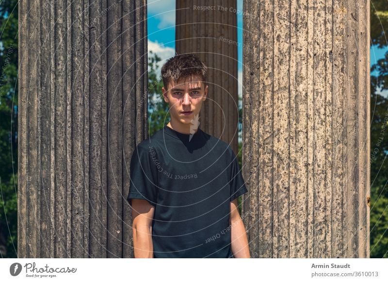 portrait of a young man standing between ancient columns architecture beautiful black blue boy casual caucasian clothes concentration confident dress journey