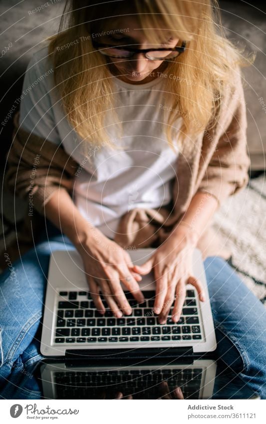 Busy female freelancer typing on computer thoughtful woman laptop project using work online self employed browsing cozy floor apartment sit carpet internet