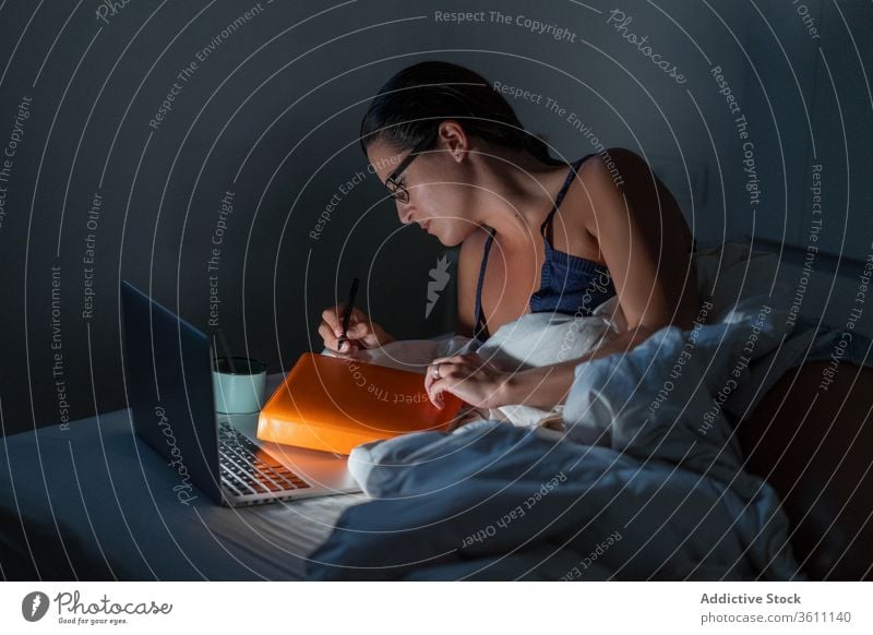 Busy female freelancer working in bed businesswoman night remote laptop browsing using entrepreneur lying down gadget late computer online internet device