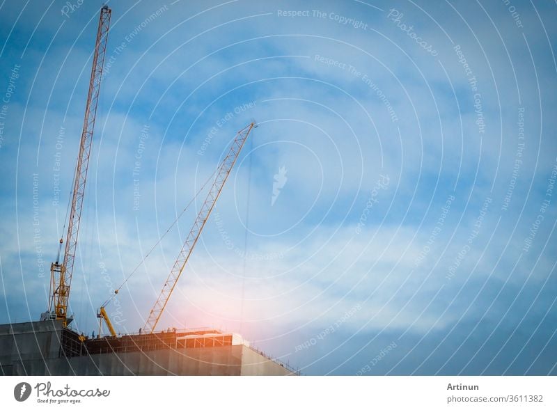 Construction crane on high-rise building with blue sky and white clouds. Construction site of commercial building or condominium or apartment in the city. Real estate business. Architecture background