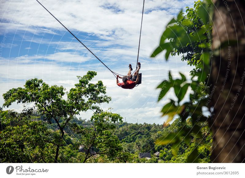 Young  male tourist swinging on the cliff in the jungle adrenaline adventure bali beautiful eruption extreme freedom fun funny green indonesia island leisure