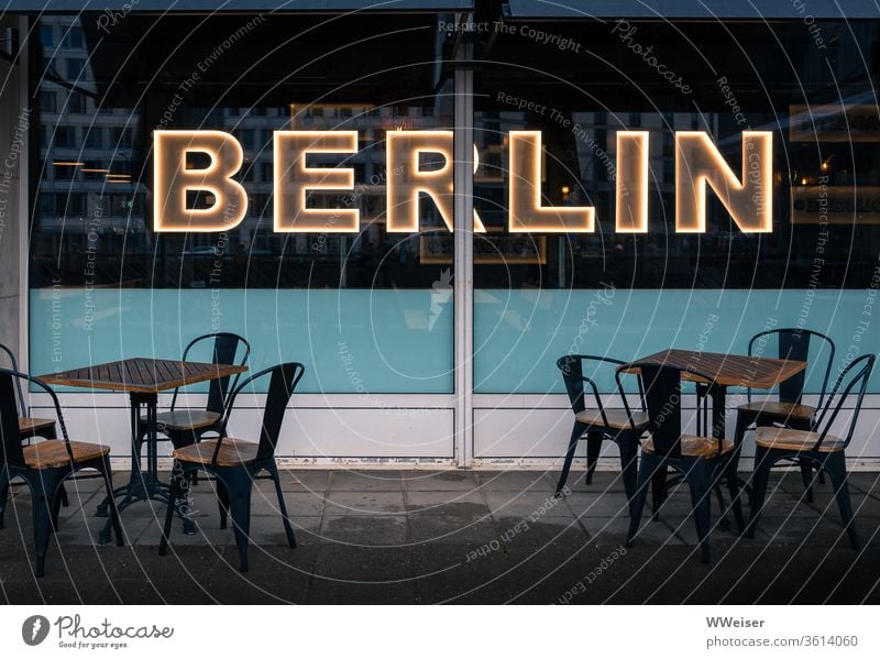 Café with illuminated Berlin lettering, evening light Sidewalk café chairs tables Empty Gastronomy Restaurant Exterior shot Tourism Street Lifestyle rainy