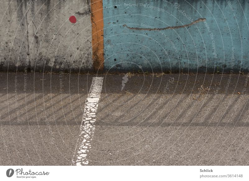 Two asphalt parking spaces in front of a colourful concrete wall and the shadow of a railing Parking lot Asphalt Wall (barrier) Concrete variegated detail mark