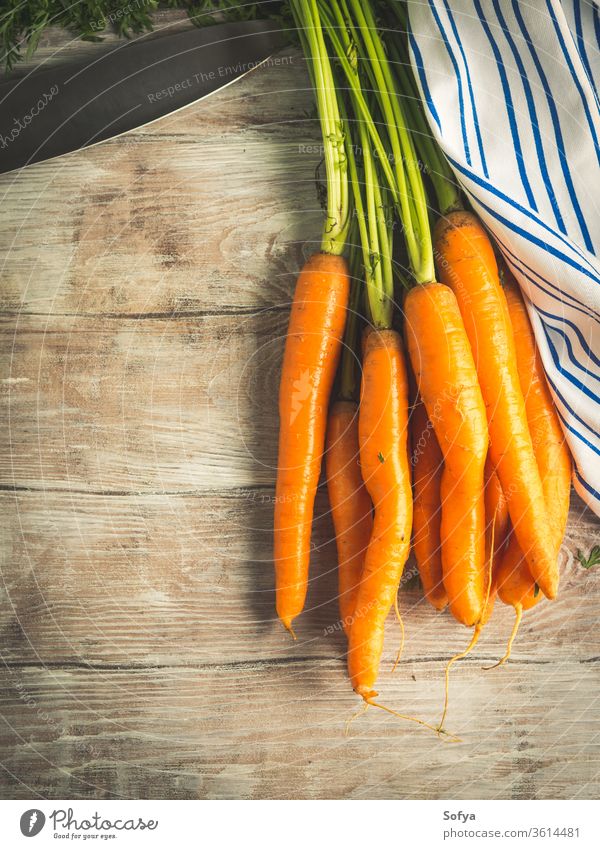 Raw carrots on rustic wooden background vegetable cook food raw organic harvest garden napkin textile cloth eat healthy uncooked kitchen knife cut chop board