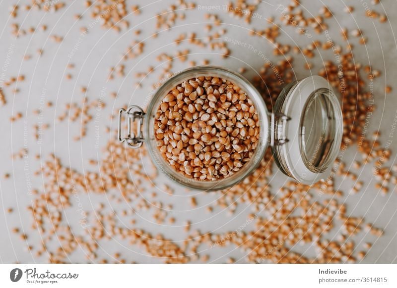 Organic corn seeds and a glass jar container on a grey background food brown isolated grain ingredient dry cereal healthy organic heap white vegetarian raw